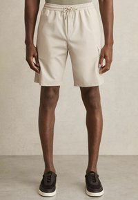 Beige cargoshorts med elastisk talje og snor, med sidelommer. Glat stof med en afslappet pasform.