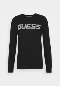 Schwarzer Strickpullover mit langen Ärmeln und Rundhalsausschnitt. Mit "GUESS"-Logo in hellgrau über der Brust. Glatte Textur.