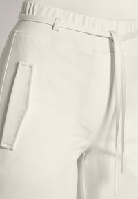 Weiße, weiche Stoff-Jogginghosen mit Drawstring-Taillenzug, seitlichen Taschen mit Klappdetail und glatter Textur.