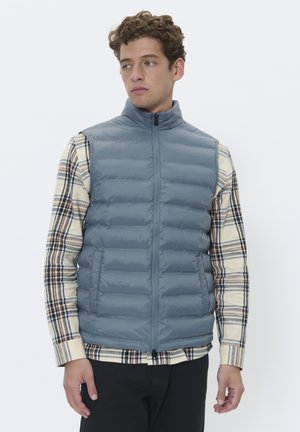 Padded sleeveless vest in light gray with a high collar and zipper front, featuring side pockets and smooth, shiny texture.