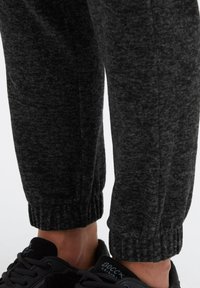 Dunkelgraue Jogginghosen aus weichem, strukturiertem Stoff mit gerippten Bündchen, kombiniert mit schwarzen Schnürsneakern mit Logo-Details.