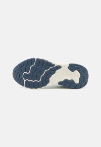 Suela de zapato con un patrón de goma texturizada en azul oscuro y una mediasuela blanca. Presenta un diseño hexagonal y ondulado para mayor tracción.