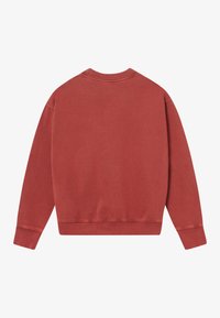 Απλή μακριά μπλούζα τύπου crewneck σε ξεθωριασμένο τούβλινο κόκκινο, προφίλ από πίσω, με ριχτές μανσέτες και ζώνη.