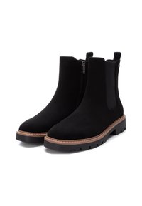 Stivali alla caviglia in suede nero con una finitura liscia, cerniera laterale, pannelli elastici e una suola testurizzata marrone a contrasto. Design con punta rotonda.