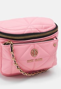 Quilted pink faux leather shoulder bag with gold-tone hardware, a top zipper, and a chain-accented strap. Features a front pocket.