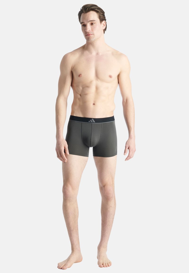 Männliche graue Boxershorts mit einem schwarzen elastischen Bündchen und dezentem Branding, figurbetontem Design und glatter Textur.