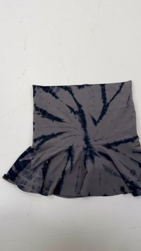 Jupe en tie-dye gris en tissu doux, avec un ourlet évasé et un motif avec des rayures bleu foncé. Présentation à plat.