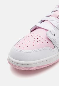 Fehér és rózsaszín sneaker sima bőr felsőrésszel, perforált orrral a légáteresztés érdekében, és rózsaszín, texturált gumi talppal.