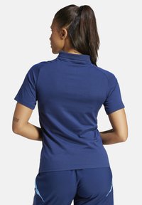 Polo shirt blu navy realizzato in tessuto testurizzato, con colletto alto, maniche corte e design delle spalle senza cuciture.