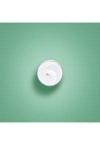 Witte room in een transparante kom, met een gladde textuur, geplaatst op een effen groene achtergrond. Geen zichtbare patronen of accenten.