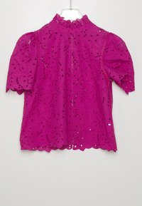 Blusa fucsia con maniche a sbuffo, ricamo ad occhio di pernice, orlo scallop e scollatura arricciata. Tessuto leggero con dettagli a motivo floreale.