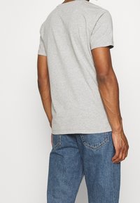 Grå bomuld t-shirt med korte ærmer og rund halsudskæringer, der har en klassisk pasform og enkelt design, parret med blå denim jeans.