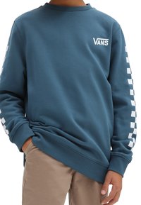Blå crewneck-tröja med vitt Vans-logotyp på bröstet, rutigt mönster på ärmarna, ribbade manschetter och mjuk tygstruktur.