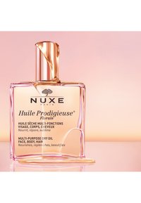 NUXE Huile Prodigieuse® Florale, eine Glasflasche mit einem roségoldenen Verschluss, enthält goldenes Öl, das für die vielseitige Anwendung im Gesicht, am Körper und in den Haaren gekennzeichnet ist.
