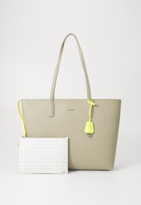 Harmaa kassi pitkällä kahvalla ja neonkeltaisella yksityiskohdalla; sisältää irrotettavan valkoisen pussukan, jossa on toistuva logokuosi. Sileä pinta.