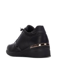 Zapatilla de cuero negra con un acabado texturizado, que presenta un diseño elegante, una suela con cuña y detalles metálicos en el talón.