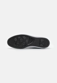 Černá gumová podešev boty s vzorovaným profilem, se zarážkou bílé barvy a texturovaným povrchem, označená "Converse All Star."