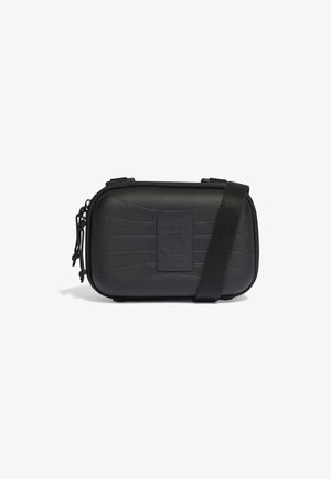 Bolso bandolera compacto negro de Adidas con superficie texturizada, parche con el logo frontal, cierre con cremallera y correa de hombro ajustable.
