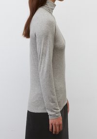 Grauer Rollkragenpullover aus weichem Stoff mit langen Ärmeln, figurbetontem Design und minimalen Nähten, präsentiert vor einem schlichten weißen Hintergrund.