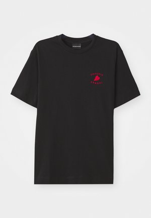 T-shirt en coton noir avec un col rond et des manches courtes ; présente le logo "Emporio Armani" brodé en rouge et un cœur au niveau de la poitrine.