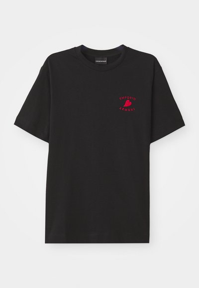Juodas medvilnės marškinėliai su apvaliu kaklu ir trumpomis rankovėmis; krūtinės srityje yra raudona siuvinėta "Emporio Armani" logotipas ir širdelė.