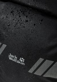 Tissu noir avec des gouttes d'eau, comportant un logo "Jack Wolfskin" et trois rayures diagonales de couleur plus claire pour le contraste.