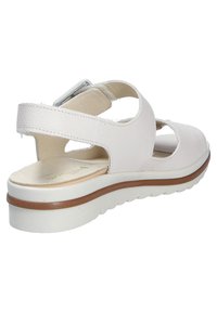 White leather sandal with open design, adjustable strap, cushioned insole, and a textured sole, featuring a light-colored platform and brown accents.