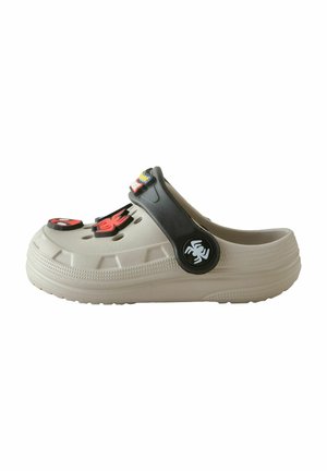 Beige slip-on træsko med sort hælrem, dekoreret med røde og sorte edderkoppe- og tegneseriefigurcharms på toppen og remmen.