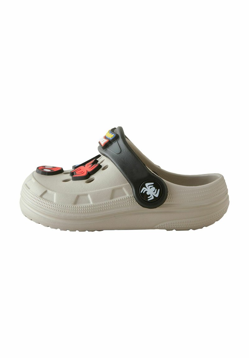 Helle beigem Clogs mit einem schwarzen Riemen, Belüftungslöchern und dekorativen Verzierungen eines Spinnentiers sowie bunten Aufnähern auf der Oberfläche.