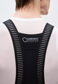 Πίσω όψη ατόμου που φορά λευκή βάση πλέγματος και μαύρη ποδηλατική ενδυμασία με το λογότυπο «Castelli Performance Innovation Design».