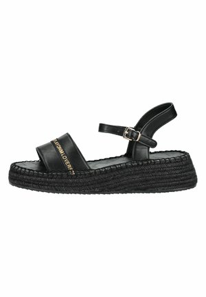 Sandale à plateforme noire avec semelle tissée, large bride avant avec texte doré et bride réglable à boucle à la cheville.