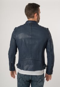 Giacca da motociclista in pelle blu navy con un design aderente, cuciture visibili, cerniere laterali e dettagli con cintura in vita. Finitura testurizzata.