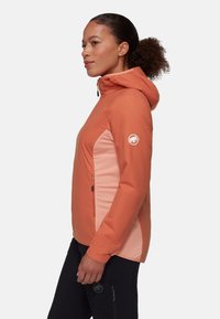 Huvan jacket i korall och ljusrosa, med framdragkedja, sidfickor och en logotyp på ärmen. Slät textur och en figurnära design.