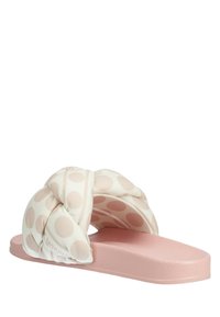 Knotte slide sandaal met een zachte stoffen bovenkant met een stippenpatroon in roomwit en lichtroze, rustend op een gestructureerde roze zool.