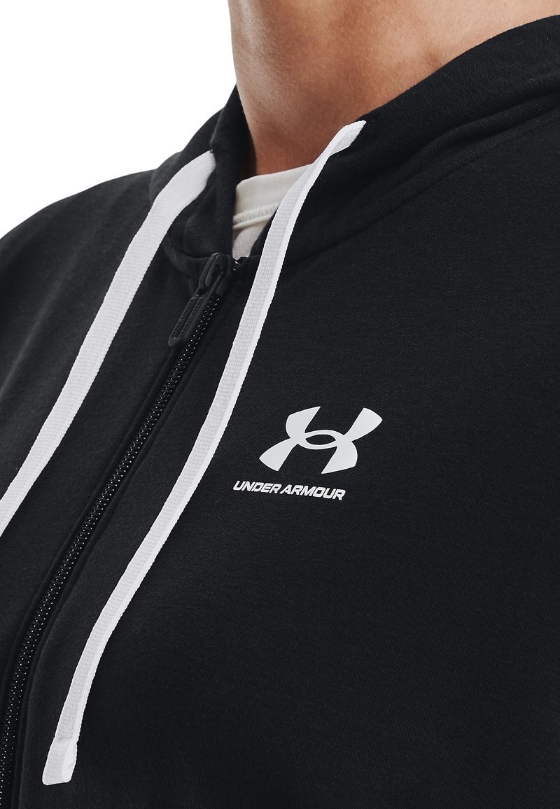 Sudadera negra con cremallera, fabricada en una mezcla de algodón, que presenta cordones blancos y un pequeño logo blanco de Under Armour en el pecho. Textura suave.