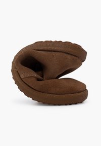 Pantofole in suede marrone con punta arrotondata e suola in gomma testurizzata, progettate con curve morbide per il comfort e la facilità d'uso.