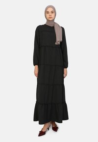 Gaun maxi hitam terbuat dari kain lembut, dengan lengan panjang, lapisan berenda, dan hem yang melebar. Dilengkapi dengan hijab abu-abu muda.