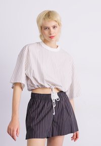 T-shirt cropped a righe in beige chiaro con orlo a coulisse, abbinato a pantaloni corti a righe grigio scuro con cintura elastica.