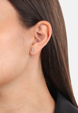 Orecchino a forma di mezzaluna in argento con piccole gemme trasparenti. Progettato per una vestibilità aderente, presenta una superficie lucida e uno stile minimalista.