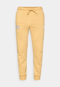 Žlté tepláky so sťahovacou šnúrkou a elastickými manžetami, text "BOSTON" na ľavom stehne a malé biele logo Nike na pravom stehne.