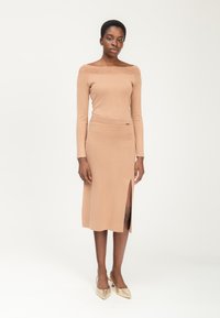 Gehaakte off-shoulder top in beige, gecombineerd met een bijpassende knie-lange rok met een zijsplit en een gedetailleerde textuur in de taille.