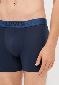 Tengerészkék boxer alsó, puha, rugalmas anyagból készült, kék heathered derékgumival, amelyen feketével szerepel a "LEVI'S" logó.