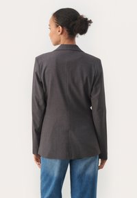 Tmavě šedý blazer se strukturovaným designem, s jedním rozparkem na zadní straně a dlouhými rukávy, ve stylu s světle modrými džíny.