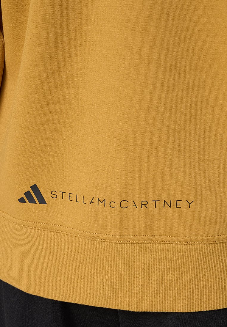 Sudadera amarilla de tejido suave con dobladillo acanalado y logo impreso "STELLAMCCARTNEY" con un gráfico de tres rayas en la parte inferior.