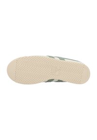 Sole della scarpa con una superficie di gomma testurizzata in crema, con tomaia in suede verde e strisce bianche sui lati. Motivo a lisca di pesce visibile.