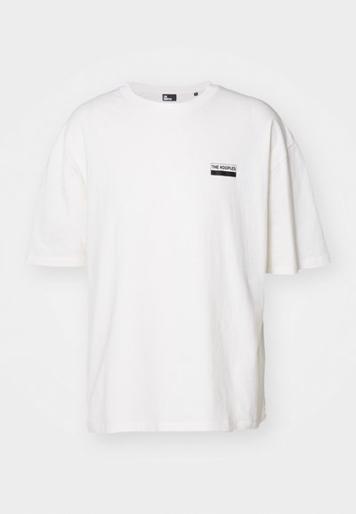 Weißes Baumwoll-T-Shirt mit einem lockeren Schnitt, Rundhalsausschnitt und kurzen Ärmeln. Verfügt über ein kleines schwarzes Etikett auf der linken Brust.