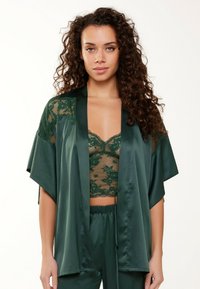 Robe en satin vert avec des accents en dentelle, présentant des manches larges et une coupe ample. Le sous-vêtement a un motif de dentelle florale et un bord festonné.