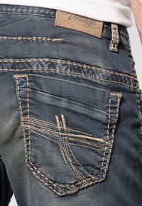 Jeans dżinsowe w ciemnoniebieskim odcieniu z widocznym przeszyciem, z projektem tylnej kieszeni i skórzaną metką z napisem "Vintage."