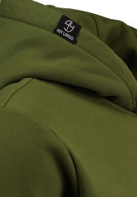 Sudadera verde oliva con una textura suave, que presenta capucha y una etiqueta negra con "KEY LARGO" en el cuello. Diseño simple y casual.