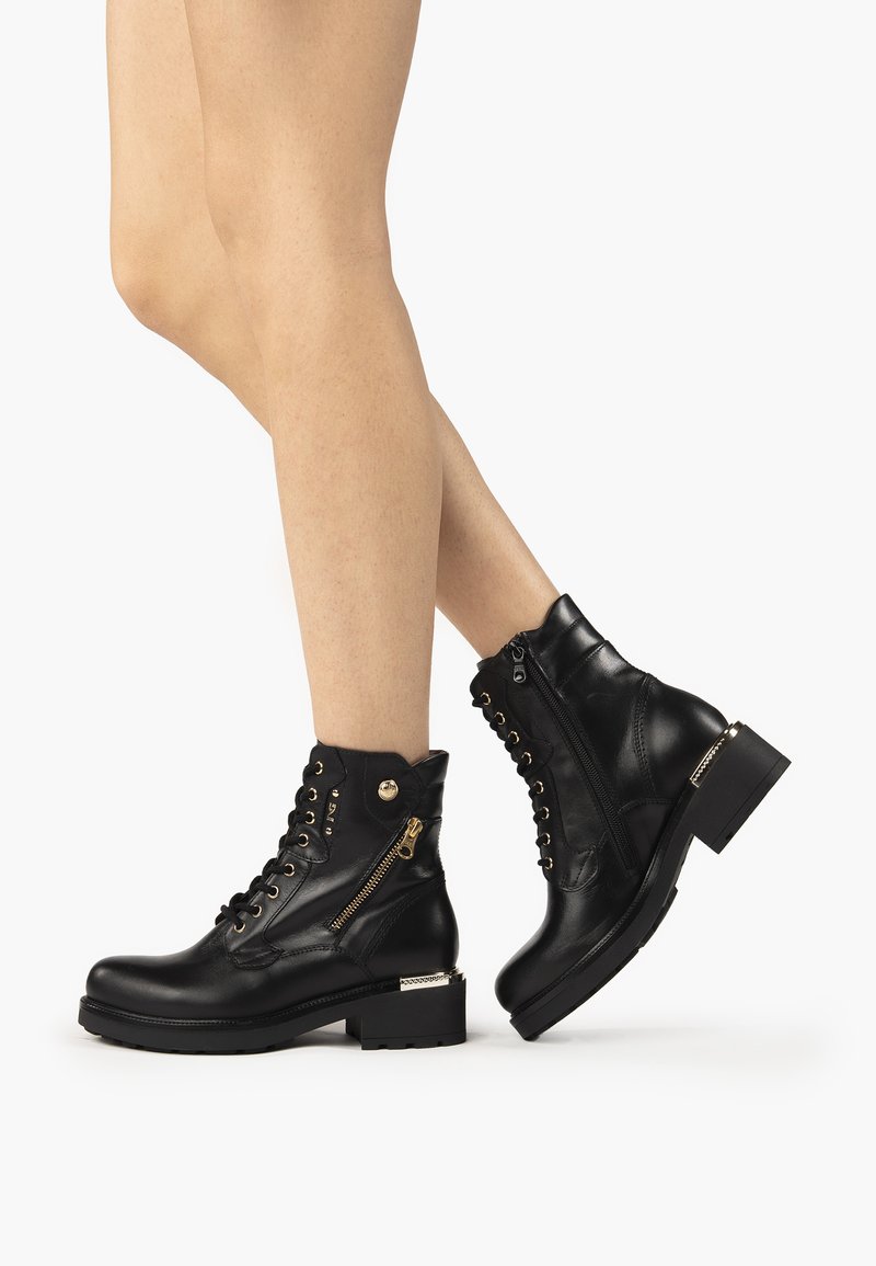 Black leather ankle boots with a chunky heel, lace-up front, and side zipper. Features gold-tone hardware and stitching detail.